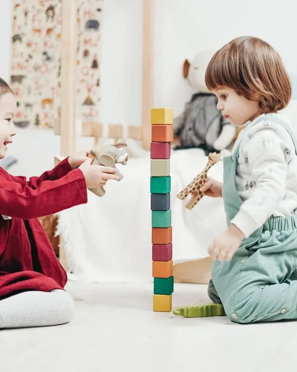 Two happy toddlers playing together with building blocks
